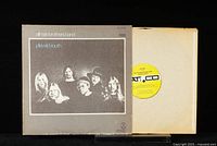 Vinyl record partially out of its cover showing yellow Atco label on record and black/white album cover featuring band photo.
