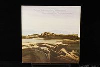 Front cover of The Moody Blues Seventh Sojourn LP featuring surreal rocky landscape with soft colors and subtle text at top.