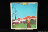 Front cover of UFO 'Phenomenon' vinyl LP record showcasing the album artwork with a woman and homes under blue sky.