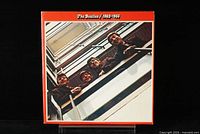 Front cover of The Beatles 1962-1966 vinyl album showing band members looking down from a balcony with red border background.