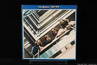 Front gatefold album cover of The Beatles 1967-1970 showing band members on balconies with blue border.