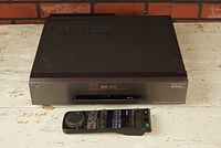 Sony SLV-R5VC SVHS Hi-Fi VCR with original remote placed on top, unit closed and power indicator light on.