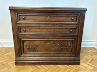 Front view of the wooden antique style filing cabinet showing two drawer fronts with keyholes, knobs, and metal handles.