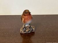 Front view of the Beswick robin figurine perched on a log, showing detailed painting and glossy finish.