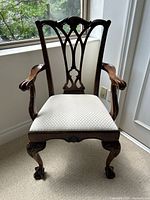 Front view of the solid wood Chippendale style armchair showing intricate carved backrest and ivory checkered upholstered seat.