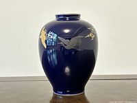 Front view of cobalt blue porcelain vase showing the smooth glossy cobalt glaze and gold bird decorations.