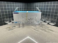 Photo showing 10 Luminarc wine glasses, some standing loose and others still boxed.