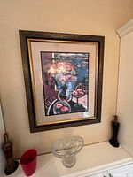 Framed print of a floral and fruit still life hanging on a wall, showing detailed colors and composition.