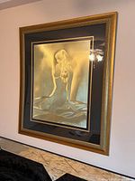Angled view of framed print showing kneeling nude woman and gold frame.