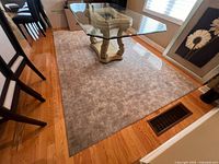 Grey checkered patterned area rug on hardwood floor under glass table, showing full view and size