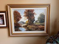 Framed original pastel landscape painting in a gold and white wide frame, showing tall trees by a water body and a path.