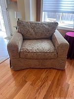 Front view of the large green upholstered armchair showing cushioned seat and backrest, and padded armrests.