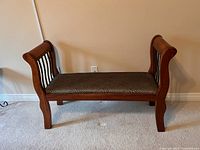 Small accent bench with wooden frame and cheetah print upholstered seat shown from a front angle, placed on carpeted floor against a wall with baseboard.