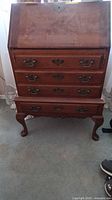 Full front view of antique wooden secretary desk with drop-front closed and 4 drawers visible.