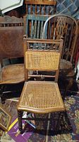 Two antique wooden chairs with cane seats and cane backrests, medium brown wood with carved details.