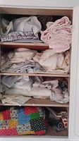 Shelves filled with folded bedding textiles including sheets, pillowcases, quilts and towels in various colors and patterns.
