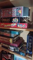 Various board games and puzzle boxes stacked on shelves, showing titles and wear