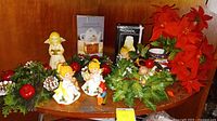 Photo of Christmas figurines, faux greenery, and boxed potpourri teapots on a wooden surface.