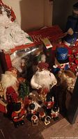 Overall assortment of Santa dolls, nutcracker figurines, and Christmas decorative sign in rustic red and white colors.