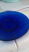 Close up image of a small cobalt blue glass plate with translucent finish and circular indentation in the center.