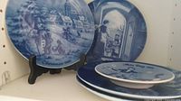 Blue and white collector plates themed for Christmas and Mother's Day, showing the Christmas 1960 plate on a stand and others stacked behind.