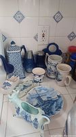 Wide angle photo showing the various ceramic pieces on kitchen counter including teapot, cups, plates, cow planter and other items