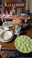 Table displaying assorted vintage dishware including egg plates, plates, serving bowls, glass jars, and decorative ceramic pieces