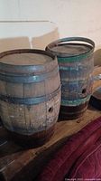 Two wooden barrels on wooden surface showing full side and top views with visible aging and metal bands