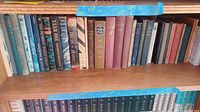 Shelf of vintage and mid-century books showing spines of various mixed bindings and titles with general wear and aging.
