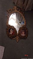 Full view of the vintage mirror with two attached oval framed art prints beneath it, showing overall style and condition