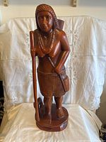 Front view of the hand-carved wooden figurine showing the person holding a staff with a dog at their feet.