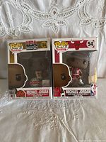 Front view of Michael Jordan Funko Pop! figures in their original boxes. One is USA Basketball Special Edition #114, the other Chicago Bulls #54.