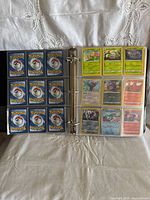 Open binder page showing 12 Pokemon cards of mixed types including green, blue, and gray card backs.