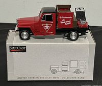 Side view of the red and black 1953 Jeep stake bed truck bank on original box showing Canadian Tire logo and stake bed with accessories.