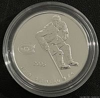 Obverse side of the coin showing Jean Beliveau skating with Montreal Canadiens logo, year 2005, and name with jersey number.