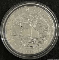 Reverse side of 2015 Canadian silver proof coin featuring man in canoe with dog and water design, denomination 10 dollars, year 2015, and maple leaves.