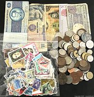 Photo showing 5 assorted foreign paper banknotes, a bag of approximately 100 postage stamps, and a pile of around 75 mixed foreign coins.