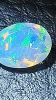 Close-up image of natural faceted Ethiopian opal showing vivid multicolored play of color on black background