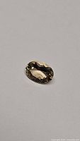 Photo of a loose oval cut natural champagne morganite gemstone on a white background showing color and faceting details.