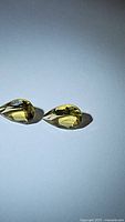 Photo of two natural pear cut golden citrine gemstones placed side by side on a flat white background, showing transparency and color.