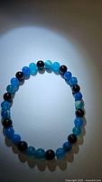 Ocean blue agate and jet black onyx bead bracelet photographed in close-up under directional light showing bead color and finish.
