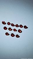 14 round-cut natural rubies displayed spread out on a light surface, showing their deep red color and round faceted shape.