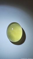 Photo of oval cabochon lemon citrine gemstone, showing smooth dome and bright lemon-yellow color.