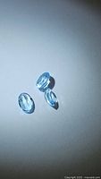 Three oval cut natural sky blue topaz gemstones arranged on a plain white background showing their size and color.