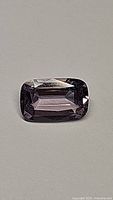 Close-up front photo of the rectangular cushion cut platinum pink purple spinel gemstone on a neutral background showing its color, cut and clarity.