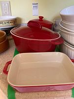 Wide view of Staub baking dish and Maxwell & Williams red covered casserole dish with lid.