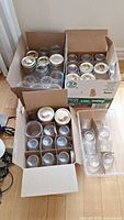 Three boxes containing approximately 36 Bernardin glass canning jars and metal lids, some jars without lids.