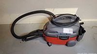 Side view of Craftsman red and gray shop vacuum with hose attached and cord wrapped on top