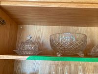 Wood shelf holding two crystal cut glass pieces: a covered butter or candy dish with a lid on the left and a footed serving bowl on the right.