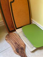 Photo showing the full set of cutting boards leaning against a wall on the floor including cork, composite, plastic, and wooden boards.